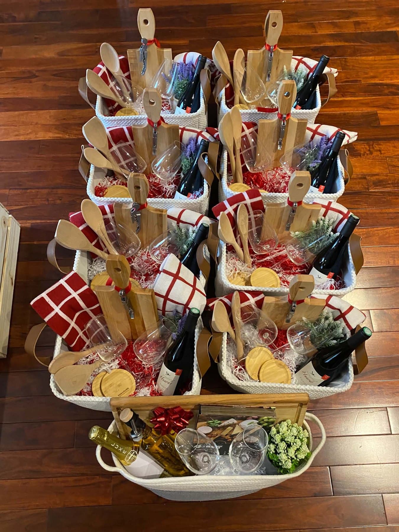 Rows of gift baskets holding engraved boards, utensils, glasses and wine