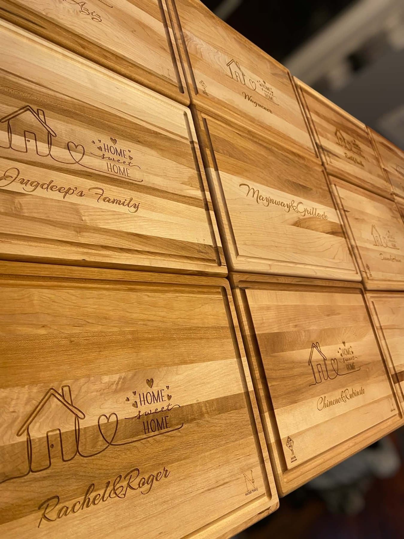 A stacked run of maple boards, each engraved with a different family name
